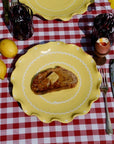 Yellow plate with a piece of toast on a red and white checkered tablecloth.