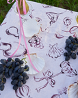 A tablecloth with a pattern of martinis, oysters, wine, and playing cards displayed on a table outdoors.