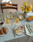 Dining table set for breakfast with croissants, eggs, and a vase of flowers.
