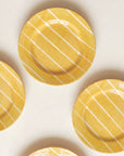 Yellow ceramic plates with white stripes on a light beige background