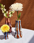 Three decorative vases with flowers on a textured surface