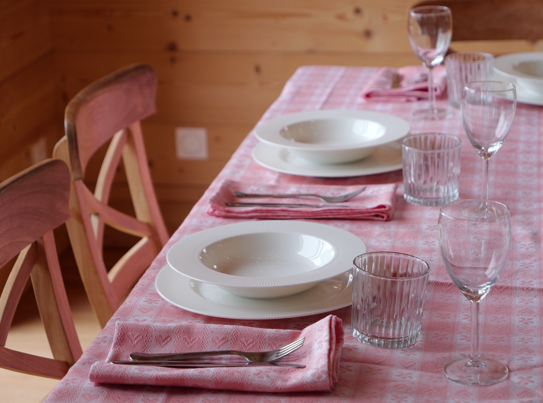 Marla Primrose Alpine Pink Chalet Napkins folded on a rustic wooden table, evoking cozy mountain dining