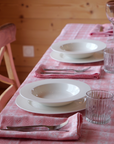 Marla Primrose Alpine Pink Chalet Napkins folded on a rustic wooden table, evoking cozy mountain dining