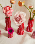 Red striped vases with flowers on a light background