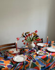 Colorful tablecloth with floral arrangement and balsa home plates on a table.
