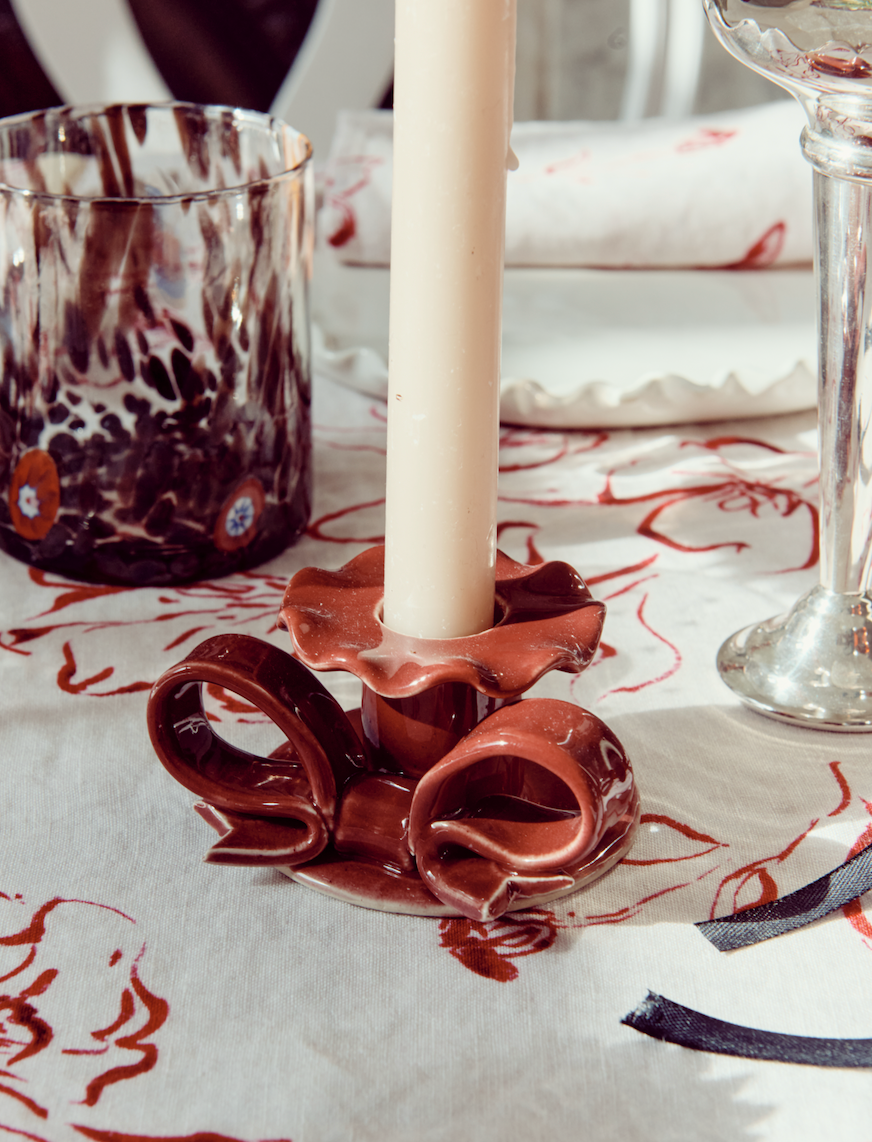 Burgundy red ceramic bow-shaped candle holder on dining table