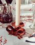 Burgundy red ceramic bow-shaped candle holder on dining table