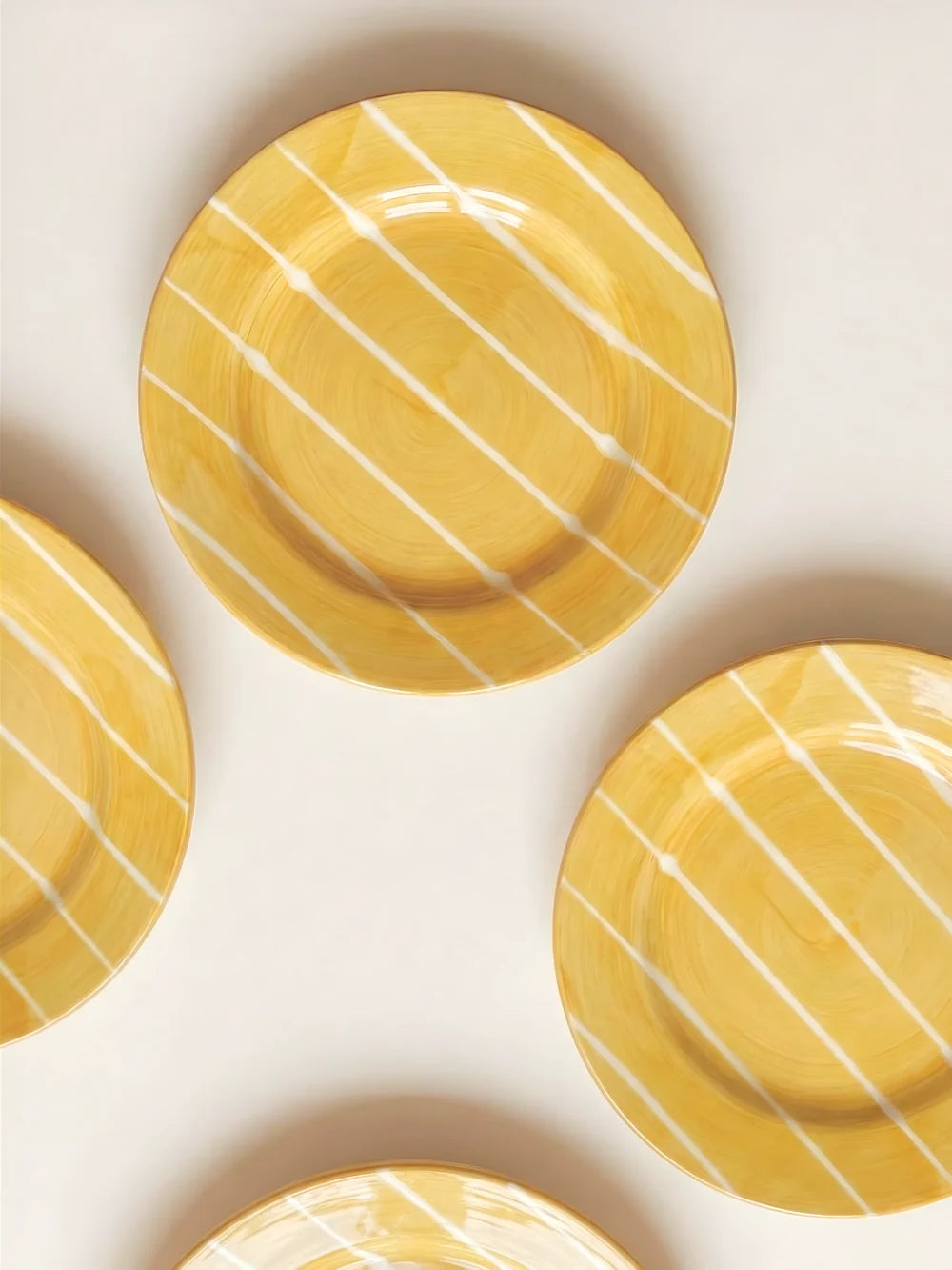 Yellow ceramic plates with white stripes on a light beige background