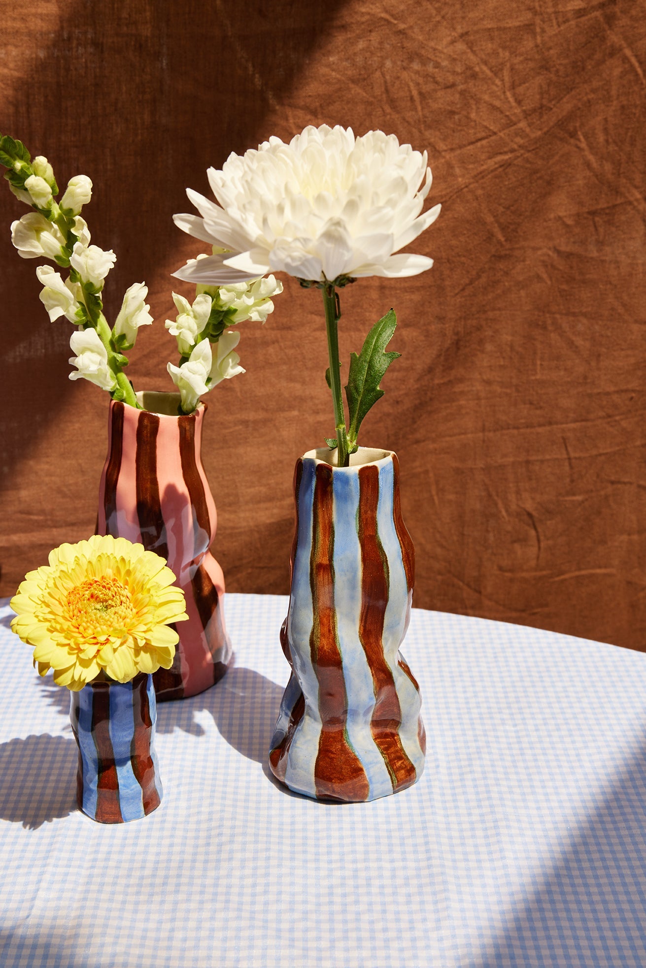 Three decorative vases with flowers on a textured surface