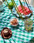 Outdoor setting with a green and white checkered tablecloth, watermelon slices, and a colorful glass.