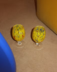 Two yellow glass knobs with a colorful pattern on a brown surface.