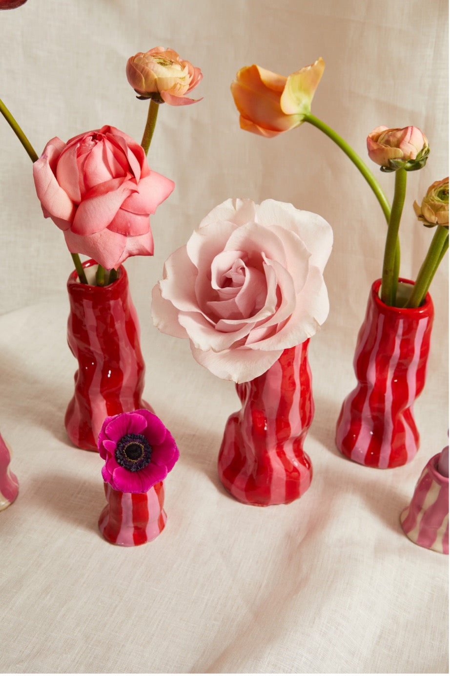 Red striped vases with flowers on a light background