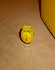 Small glass with yellow pattern on a beige carpet